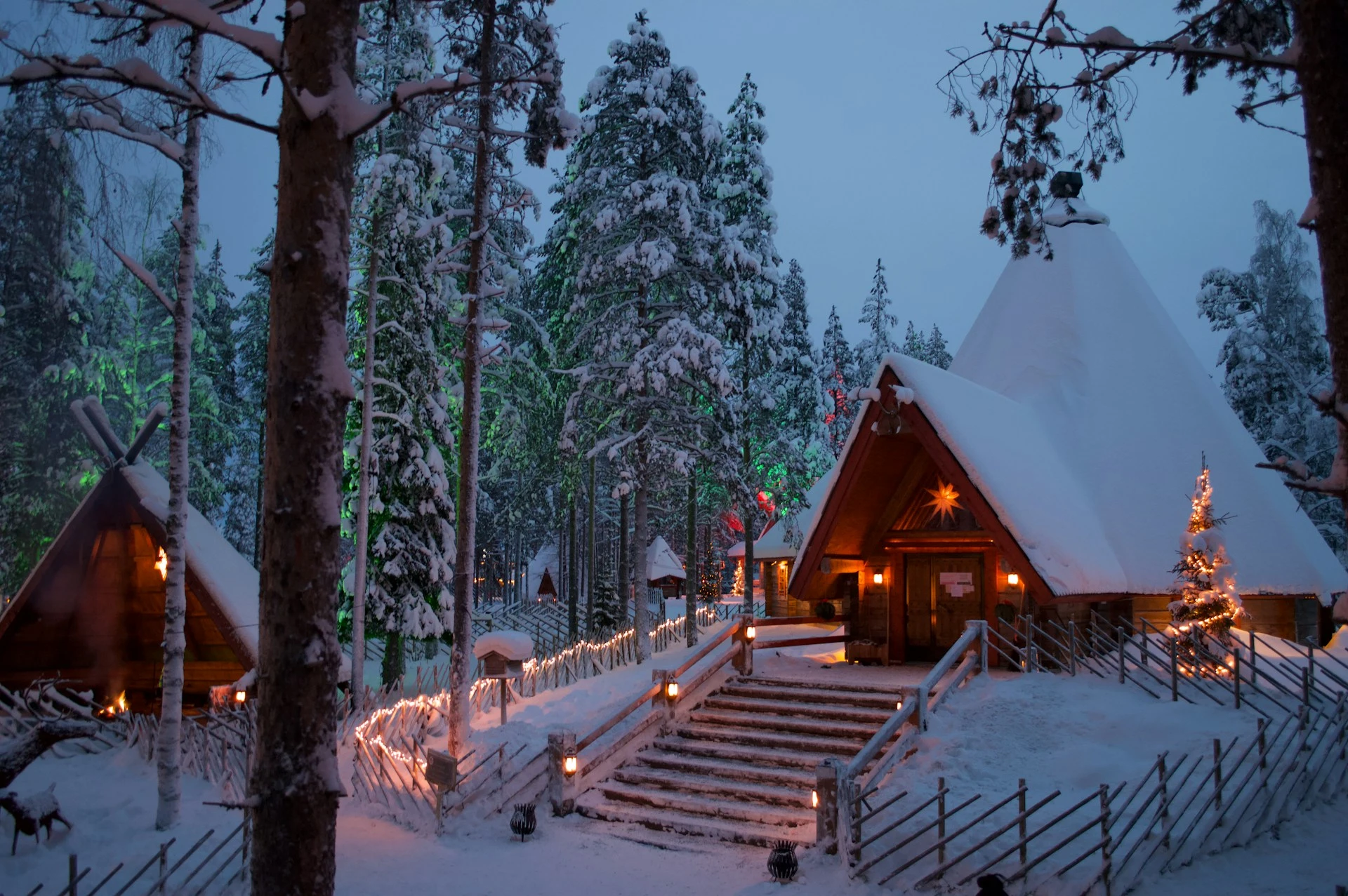Santa Claus Village in Rovaniemi, Finland, covered in snow and illuminated with holiday lights.